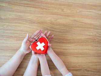 Red Cross in heart shape being held by mother and child